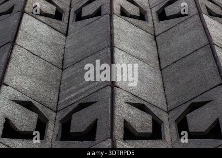 Primo piano dettagliato di un'intricata parete geometrica in cemento con motivi e trame unici con un elemento di design accattivante Foto Stock