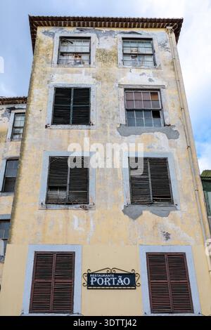 Esterno del ristorante Portão nel centro storico di Funchal, Madeira, Portogallo, che mostra un alto edificio storico con finestre con persiane e vernice sbucciante Foto Stock