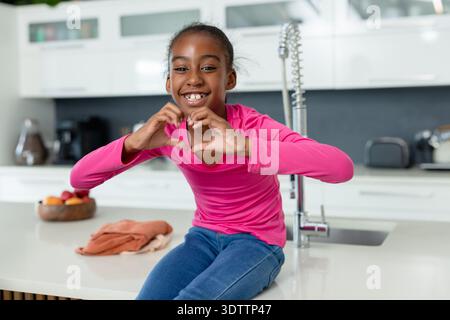 L'isola della cucina bianca lucida presenta rubinetto cromato con scollo a molla, cesto di frutta in legno e tostapane Foto Stock