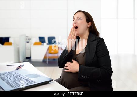 donna incinta che dorme nel suo ufficio Foto Stock