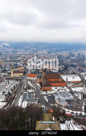 Vista aerea invernale di Innsbruck con la Basilica Wiltener e le Alpi Foto Stock