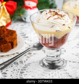Dessert torta in spugna al cioccolato della Foresta Nera o brownie con ciliegie, crema pasticcera e panna montata in un bicchiere di vetro. Banale. Anno nuovo. Natale. Una fes Foto Stock