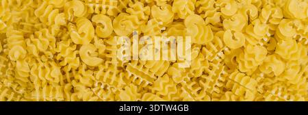 Primo piano del tradizionale radiatore di pasta cruda italiana. Pasta piccola e corta. Background culinario. vista dall'alto, immagine lunga, banner Foto Stock