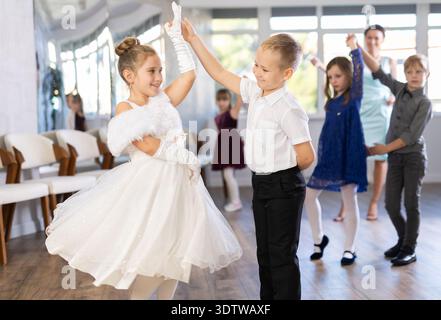 Entusiasti bambini preadolescenti che ballano valzer a coppie nella scuola di danza Foto Stock
