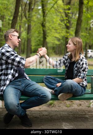 Padre felice e figlia piccola seduti su Una panchina a fare Una stretta di mano in Family Look Foto Stock