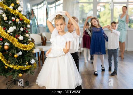 Ballo di Natale - i bambini vestiti splendidamente ballano il valzer viennese vicino all'albero di Capodanno Foto Stock