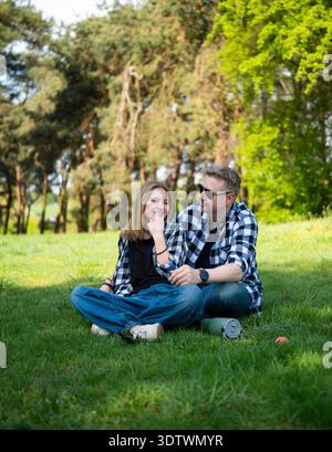 Padre felice e figlia amano passare del tempo insieme seduti sull'erba nel parco Foto Stock