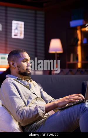 Un trader maschile di colore che monitora i cambiamenti in tempo reale del mercato azionario sui notebook, investendo fondi con l'obiettivo di aumentare i guadagni. Un giovane concentrato che studia i valori economici per il progresso globale. Foto Stock
