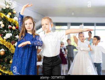 Ballo di Natale - i bambini vestiti splendidamente ballano il valzer viennese vicino all'albero di Capodanno Foto Stock