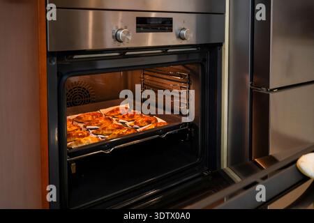 Le empanadas fatte in casa cuocono alla perfezione in un moderno forno da cucina. L'immagine cattura i dolci appena sfornati, mostrando una deliziosa cucina casalinga Foto Stock