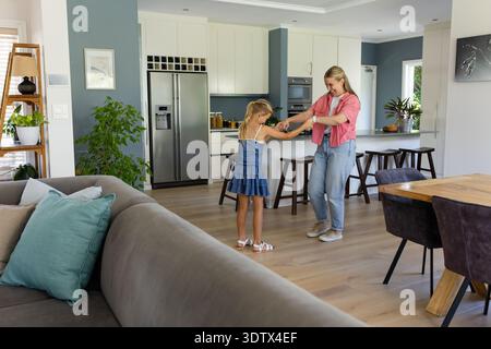 Madre che tiene la mano del bambino mentre balla vicino a Kitchen Island con un cestino di frutta, copia spazio Foto Stock