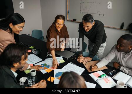Professionisti professionali sorridenti, uomini e donne, che discutono dei documenti in ufficio Foto Stock