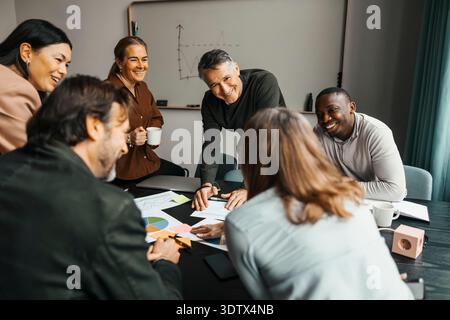 Team di professionisti aziendali sorridenti che discutono dei rapporti durante una riunione in ufficio Foto Stock