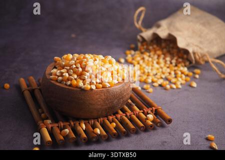 Chicchi di mais in una ciotola e sparsi su una superficie Foto Stock