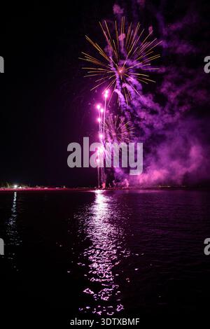 Spettacolo pirotecnico di Ferragosto sul mare a grado Italia 2025: Spettacolari fuochi d'artificio esplosivi di notte, vibranti esplosioni che si riflettono sull'acqua. Foto Stock