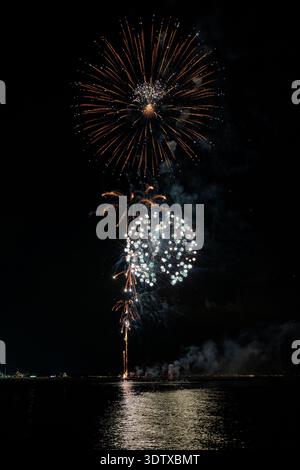 Spettacolo pirotecnico di Ferragosto sul mare a grado Italia 2025: Spettacolari fuochi d'artificio esplosivi di notte, vibranti esplosioni che si riflettono sull'acqua. Foto Stock