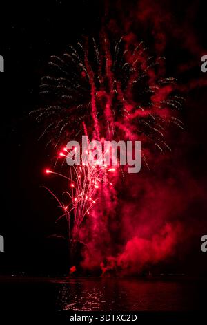 Spettacolo pirotecnico di Ferragosto sul mare a grado Italia 2025: Spettacolari fuochi d'artificio esplosivi di notte, vibranti esplosioni che si riflettono sull'acqua. Foto Stock
