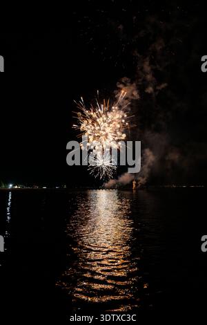 Spettacolo pirotecnico di Ferragosto sul mare a grado Italia 2025: Spettacolari fuochi d'artificio esplosivi di notte, vibranti esplosioni che si riflettono sull'acqua. Foto Stock