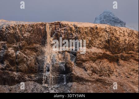 Cascata Bjarnarfoss in inverno sulla penisola di Snæfellsnes, Islanda, con scogliere di basalto innevate vicino a Búðir Foto Stock