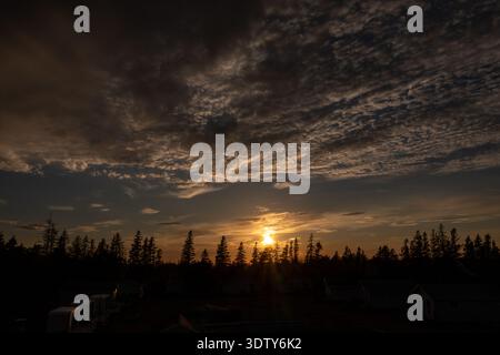 Foto aerea con drone di un vibrante tramonto sui campi e sugli alberi dell'Isola del Principe Edoardo in Canada che mostra la luce dorata che si illumina attraverso i terreni agricoli sottostanti Foto Stock