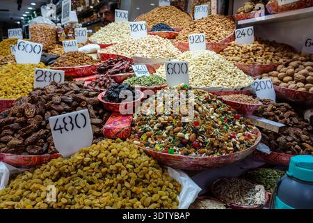 Ciotole di datteri, uva passa e noci al mercato all'ingrosso delle spezie di Chandni Chowk nella vecchia Delhi. Un uomo è visibile in lontananza. Foto Stock