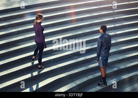 Fitness, scale e coppie in città per allenarsi, allenarsi o benessere insieme dall'alto. Sport, atleti e schiena con donna sui gradini per Foto Stock