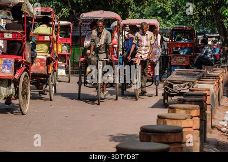 I risciò multipli trasportano i passeggeri lungo la strada alberata di Chandni Chowk, con più traffico in lontananza nella vecchia Delhi. Foto Stock