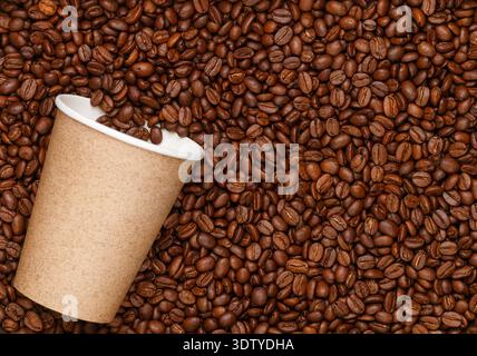 Chicchi di caffè tostati e tazze di carta. Il concetto di drink da asporto. Background culinario. Vista dall'alto, messa a fuoco selettiva Foto Stock