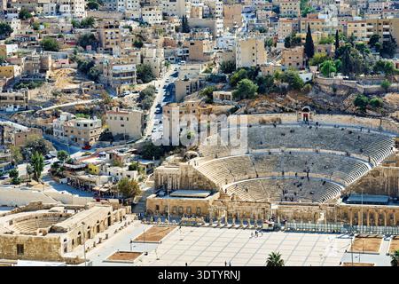I visitatori esplorano il teatro romano di Amman, in Giordania. Il sito presenta antichi gradini in pietra e offre una vista della città moderna. Foto Stock