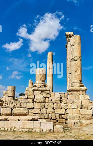 I visitatori camminano tra le antiche colonne di pietra e le rovine della Cittadella ad Amman in Giordania, godendosi il cielo azzurro sullo sfondo. Foto Stock