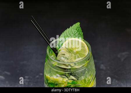 Cocktail mojito fresco con lime, menta e ghiaccio in vetro su sfondo scuro Foto Stock