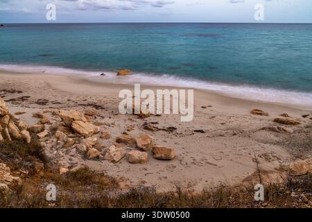 Splendida vista panoramica sulla spiaggia di Villa Michela a Santa Margherita di Pula durante l'ora d'oro. Questo scatto a esposizione lunga presenta onde delicate o Foto Stock