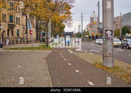 Ammira il Troendlinring a Lipsia, caratterizzato da una pista ciclabile, alberi autunnali, architettura storica e traffico in direzione del centro città Foto Stock