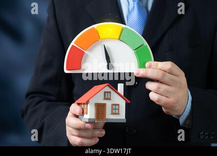 Una casa e una scala di efficienza energetica indicante valori insoddisfacenti. Perdita di calore e consumo energetico eccessivo. pla per il controllo e la ristrutturazione dell'energia domestica Foto Stock