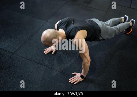 Uomo che esegue push-up sul pavimento della palestra dall'alto Foto Stock