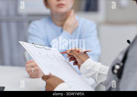 Dottoressa donna nera che scrive nella cartella pazienti durante la consultazione in clinica Foto Stock