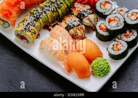 Piatto di sushi assortito con panini, gamberi di salmone nigiri e wasabi su piatto bianco Foto Stock