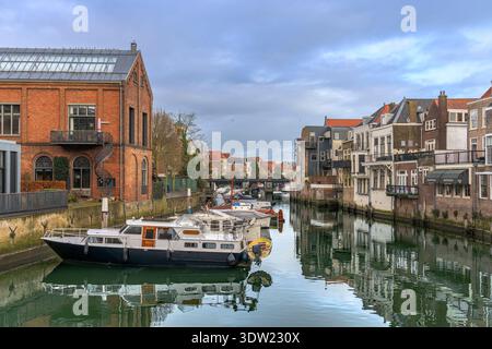 Si affaccia sul canale dal ponte pedonale di Wijnbrug. Vecchi edifici e magazzini fiancheggiano i canali. Nieuwbrug è in lontananza, Dordrecht, Paesi Bassi. Foto Stock