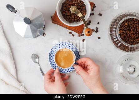 Una tazza di caffè appena fatto nelle mani di una donna. Messa a fuoco selettiva, vista dall'alto Foto Stock
