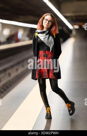 Giovane donna in piedi sulla piattaforma della metropolitana che guarda la macchina fotografica Foto Stock