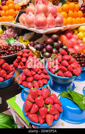 Una varietà di frutta fresca, tra cui fragole, mele, prugne e arance in vendita. Al grande mercato alimentare locale di Mehrgon. A Dushanbe, Tagikistan. Foto Stock