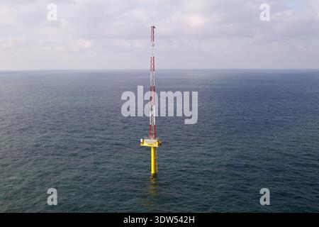 Paesi Bassi - 13 febbraio 2026: Veduta aerea di un'unica e torreggiante fondazione di turbine eoliche offshore, la sua base gialla in contrasto con la va Foto Stock