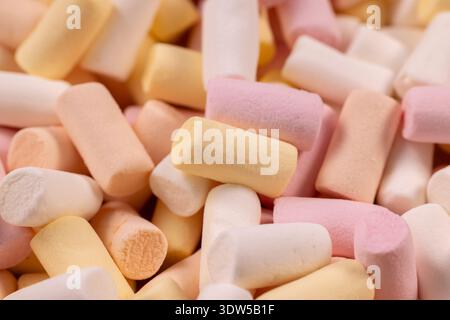 Mini marshmallow pastello adagiati su uno sfondo morbido e colorato di rosa, giallo e bianco, soffice dolcificante con zucchero sperfetto per dessert, festa o caldo Foto Stock