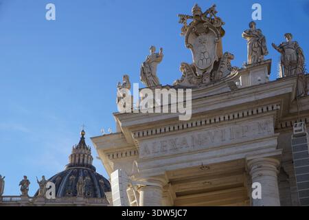 Dettaglio architettonico dell'ornato colonnato di Piazza San Pietro con la cupola e la cupola della basilica di San Pietro sullo sfondo in una giornata di sole Foto Stock