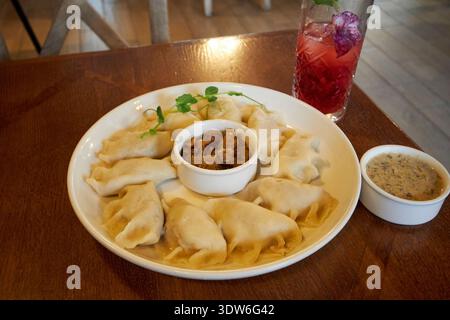 i tradizionali gnocchi bolliti di pierogi serviti con cipolle fritte e pancetta con salsa di funghi e limonata di lamponi pierogarnia mandu danzica polonia Foto Stock