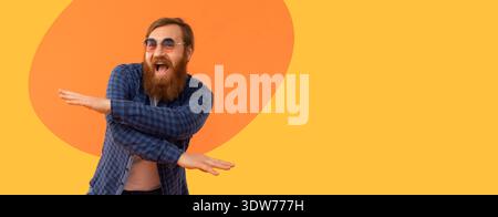 Uomo che balla di fronte a uno sfondo arancione brillante con un'espressione divertente sul viso Foto Stock