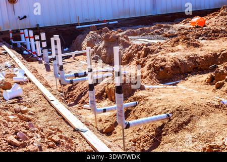 I lavoratori installano tubi di drenaggio in pvc bianco nello sporco per i collegamenti idraulici in cantiere Foto Stock