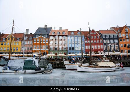 Colorati edifici storici e barche lungo il canale di Nyhavn ghiacciato in inverno a Copenaghen Foto Stock
