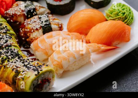 Sushi da primo piano con nigiri di gamberi di salmone e panini serviti su piatto bianco Foto Stock
