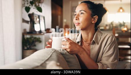 Caffè, rilassati e pensa con una donna sul divano nel soggiorno di casa per una pausa, un po' di relax o per il tempo libero. Ricordi, nostalgia e visione con la persona Foto Stock